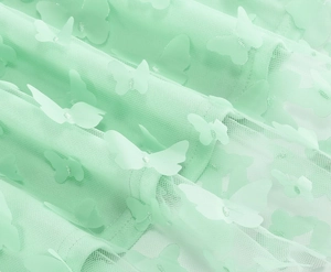 Dettaglio del tessuto in rete verde menta con applicazioni decorative di farfalle 3D