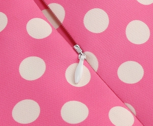 Dettaglio della cerniera invisibile bianca su un abito rosa con motivo a pois bianchi