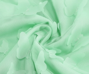 Dettaglio ravvicinato del tessuto a rete verde menta con applicazioni di farfalle 3D