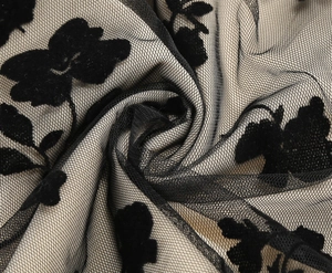 Close-up of black mesh fabric with floral flocking detail and a translucent lace texture