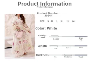 Détail de robe longue blanche avec broderie florale, manches lanternes et ceinture assortie