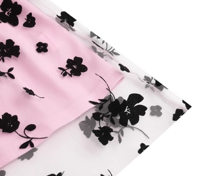 Detail of pink fabric with white mesh overlay featuring black flocked floral patterns