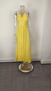 Detailed view of bright yellow halter neck dress featuring a deep V-neck and split hem