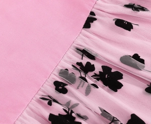 Detailed close-up of pink mesh dress with elegant black floral flocking and fine stitching