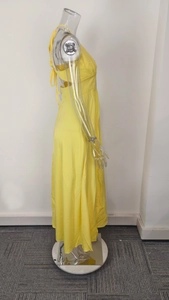 Side view of long yellow halter maxi dress with backless design and high slit detail