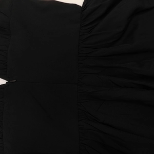 Détail de la robe noire à col en V avec tissu froncé et fermeture éclair invisible latérale