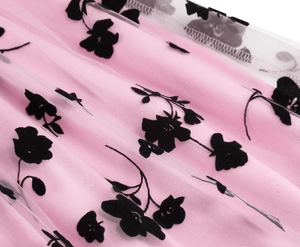 Detailed view of layered pink fabric with white mesh and black floral flocking patterns