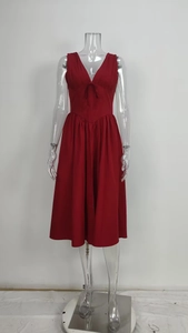 Detail of red V-neck dress featuring a delicate bow tie and elegant pleats on the bodice