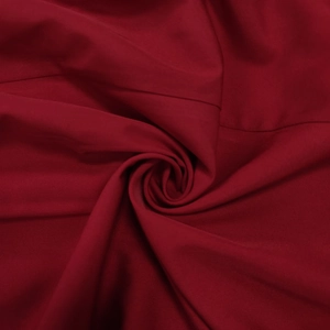 Détail macro de la texture du tissu rouge vin avec des plis en spirale pour une robe