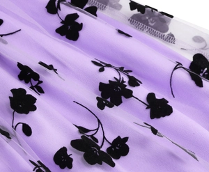 Close-up detail of purple mesh fabric with black floral flocked patterns and layered texture