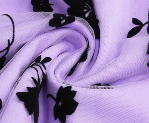 Detail of lavender tulle fabric with black floral flocking and soft draped mesh texture