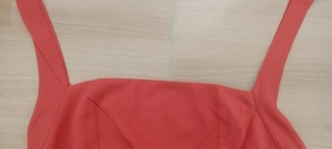 Close-up of coral red square neck dress with wide straps and smooth fabric texture