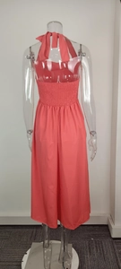 Back view of a coral halter neck dress featuring smocked waist and tie-back details.