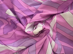Close-up of abstract geometric swirl print on lilac and pink silk fabric with soft drape