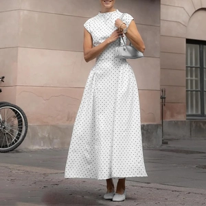 Dettaglio di un vestito vintage bianco a pois neri con collo alto e vita aderente