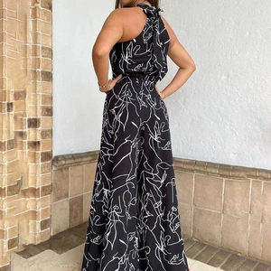 Detail of elegant backless halter neck jumpsuit with white abstract print on black fabric