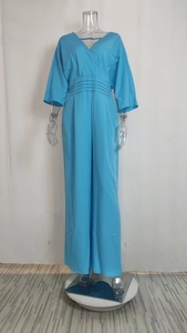 Detail view of the V-neck and tiered pleated waist design on a blue wide-leg jumpsuit