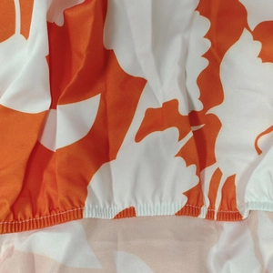 Detail of floral printed fabric with orange and white patterns and elastic hem stitching
