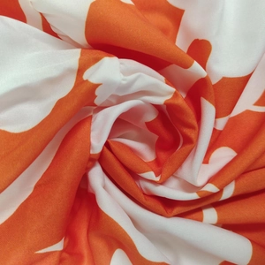 Detailed macro view of orange and white abstract floral print fabric with silky texture
