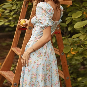 Detail of light blue floral dress featuring puff sleeves and an elegant open back design