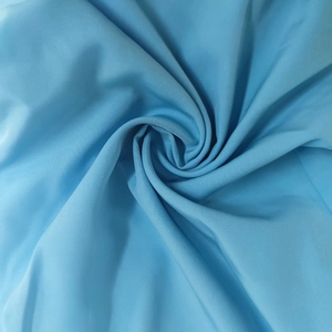 Detailed macro view of the sky blue textile fabric with fine woven texture and soft drape