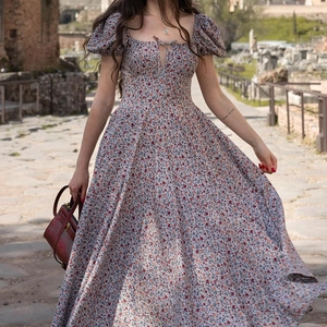 Detail of French floral dress showing square neckline and puff sleeves on stone path