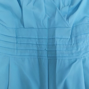 Detail view of light blue jumpsuit featuring V-neck and multi-layered pleated waist design