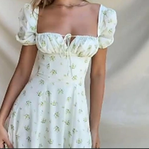 Detail of floral puff sleeve dress with drawstring square neckline and light green prints