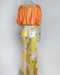 Detail view of orange floral wide-leg trousers and batwing sleeve crop top set