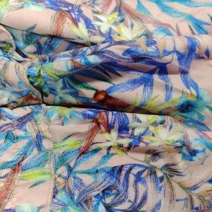 Close-up of tropical floral print on pink woven fabric with delicate hem stitching