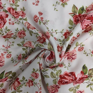 Detail of floral print fabric with red and pink roses on a soft white background texture