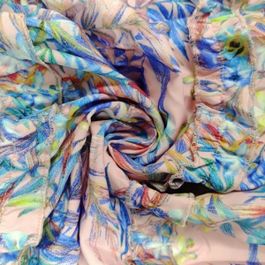 Detail of tropical floral print on pink fabric with ruffled hem and fine stitching