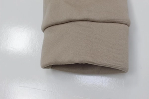 Detailed close-up of ribbed cuffs on khaki knit sweatshirt with soft fabric texture