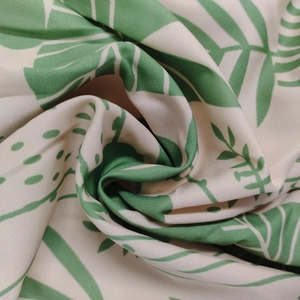 Macro shot of tropical green leaf print on beige woven fabric with elegant drape