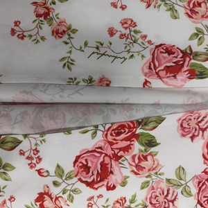 Detail shot of white floral fabric with red roses and ruffled layering design