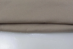 Close-up of beige knitted fabric detail showing high-quality fine stitching for hoodies