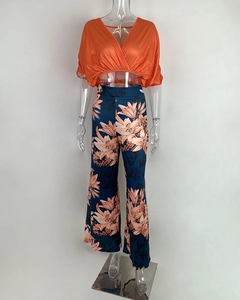 Detail of orange V-neck wrap crop top and floral print wide-leg trousers on mannequin