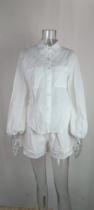Detailed view of white two-piece set featuring a button-up shirt and matching shorts