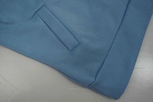Detail of light blue sweatshirt featuring ribbed hem and diagonal quilted pocket stitching