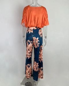 Rear view of orange short sleeve top with ruched sleeves and floral wide leg pants