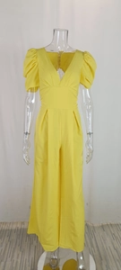 Detail of high waist yellow jumpsuit featuring deep V-neck and stylish puff sleeves
