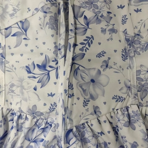 Detailed view of floral print dress featuring blue porcelain patterns and stitching details