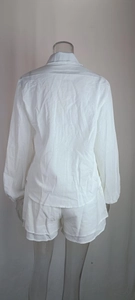 Detail of white two-piece set featuring back pleated shirt and ruffled hem shorts