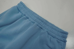 Detailed macro view of elastic waistband and stitching on light blue cotton joggers