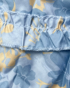 Detailed macro view of light blue floral fabric with ruffle trim and precise double stitching