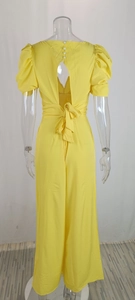 Detail of yellow jumpsuit with open back, pearl buttons and bubble sleeves