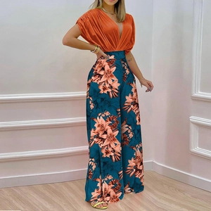 Detailed view of the deep V-neck orange top and high-waisted floral print wide-leg pants