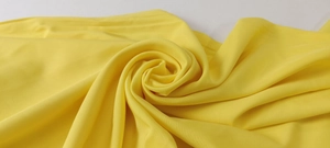 Close-up detail of light yellow chiffon fabric with soft drape and smooth plain texture