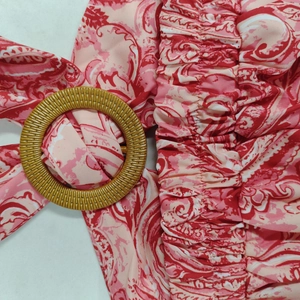 Dettaglio di abito boho con stampa floreale, vita a nido d'ape e fibbia rotonda intrecciata
