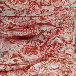 Dettaglio del tessuto a stampa paisley rossa con trama increspata e motivi floreali